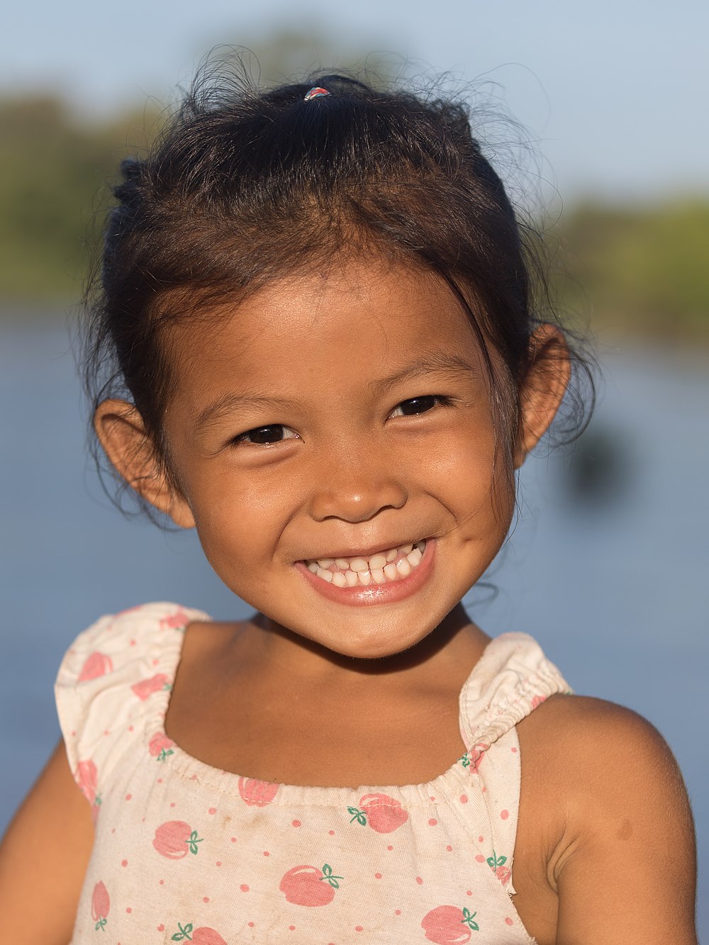 Young girl smiling with teeth at golden hour, in sunshine