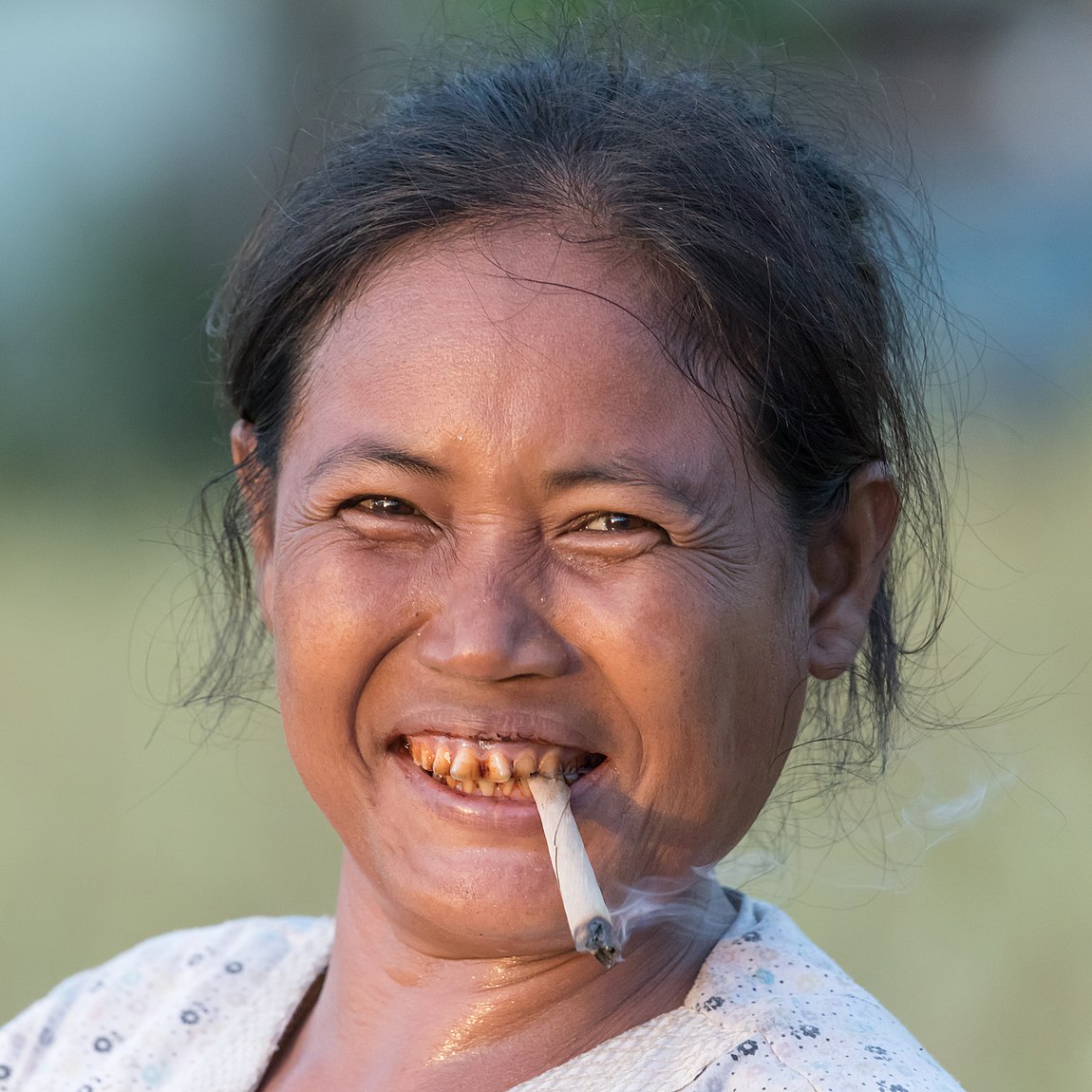 Portrait d'une femme fumant une cigarette roulée dents teintees au paan