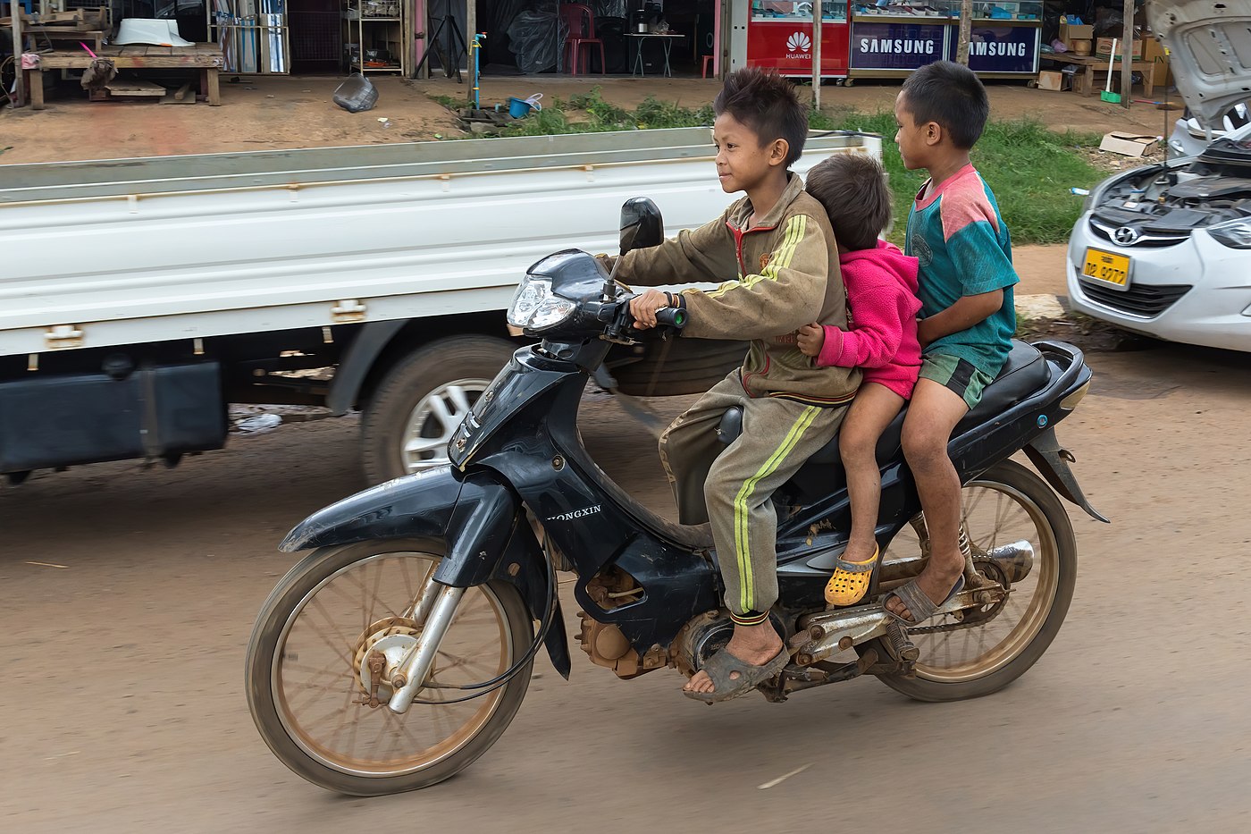 Boy riding a motorcycle with two other young children