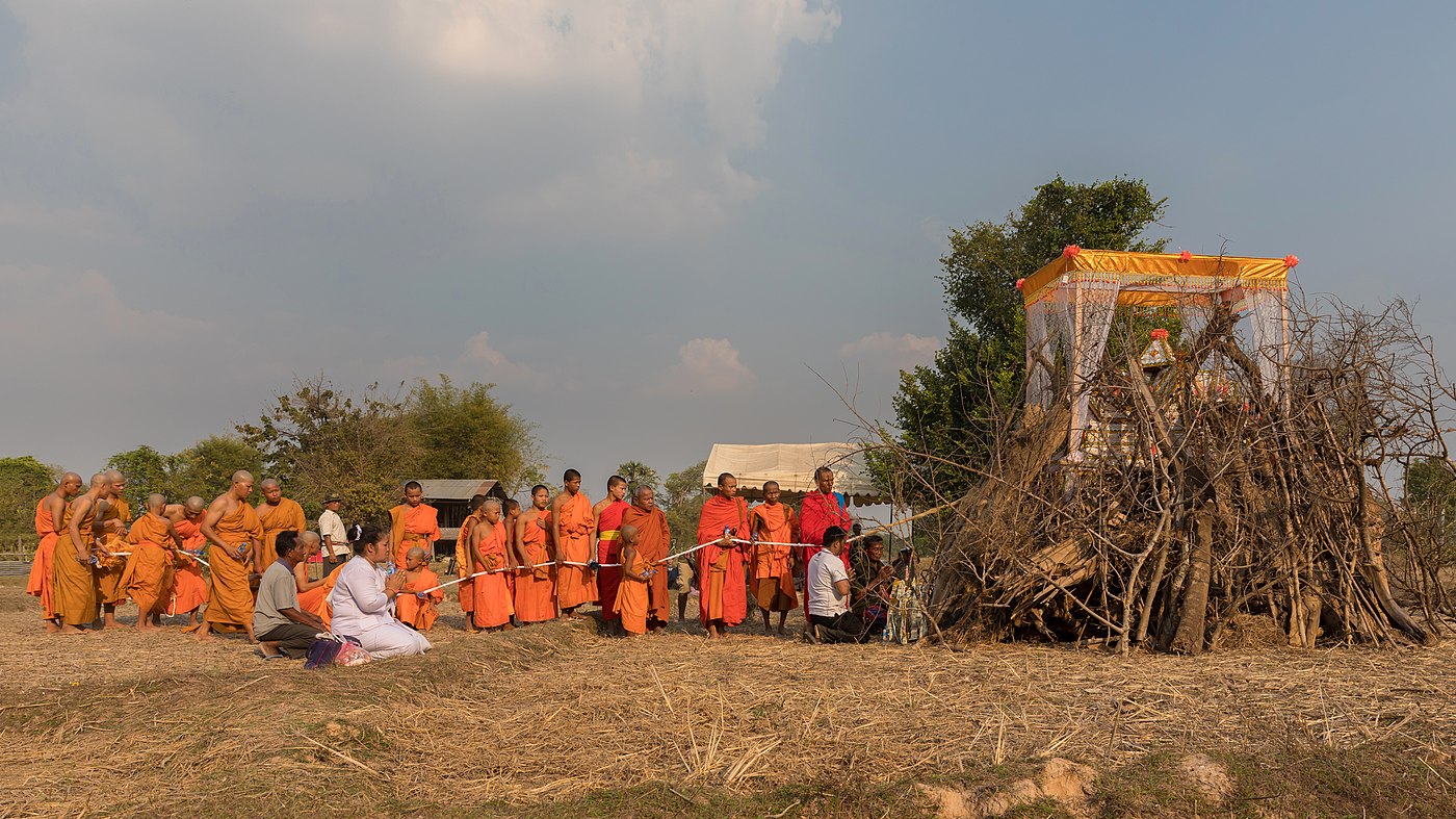 Cortège rituel de moines bouddhistes devant un cercueil sur un bûcher