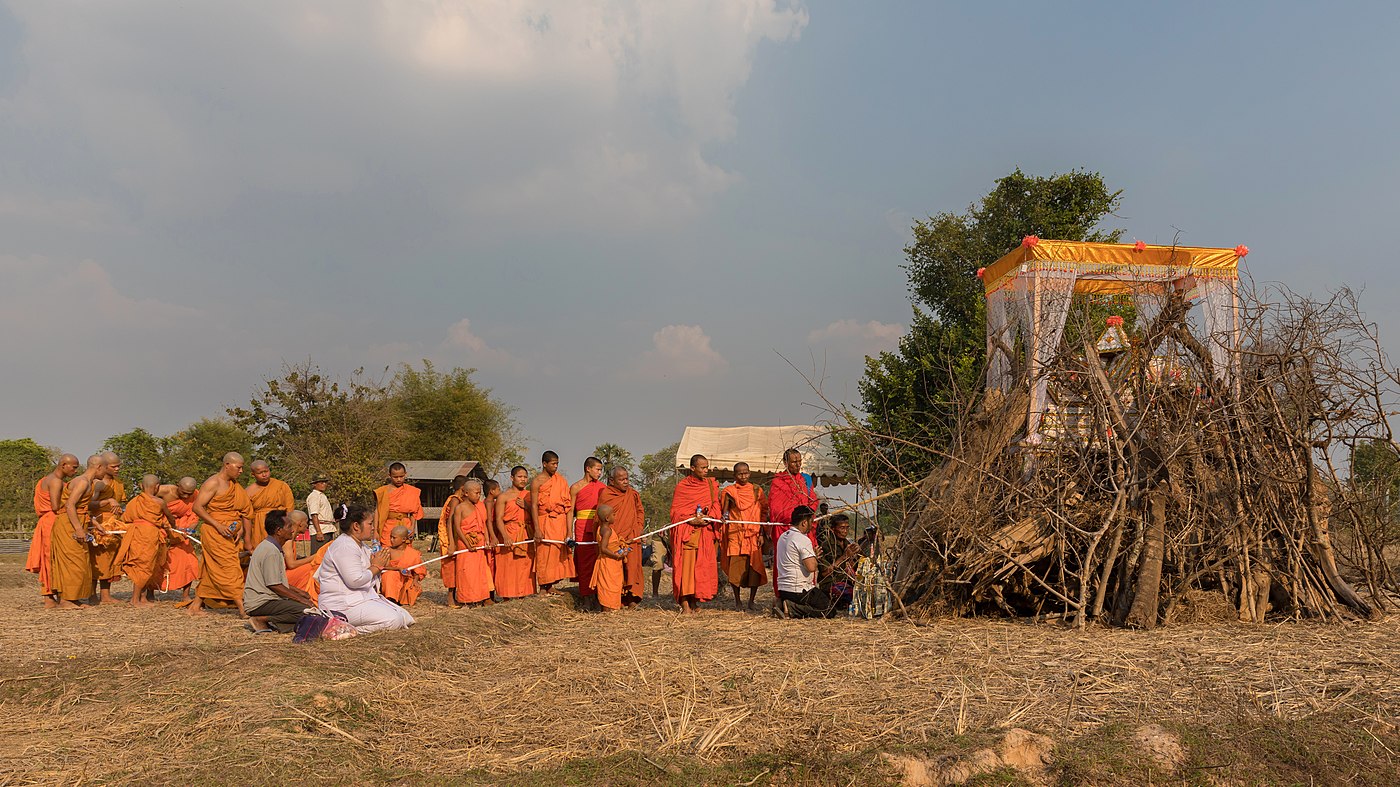 Ritual procession of Buddhist monks in front of a coffin over a pyre