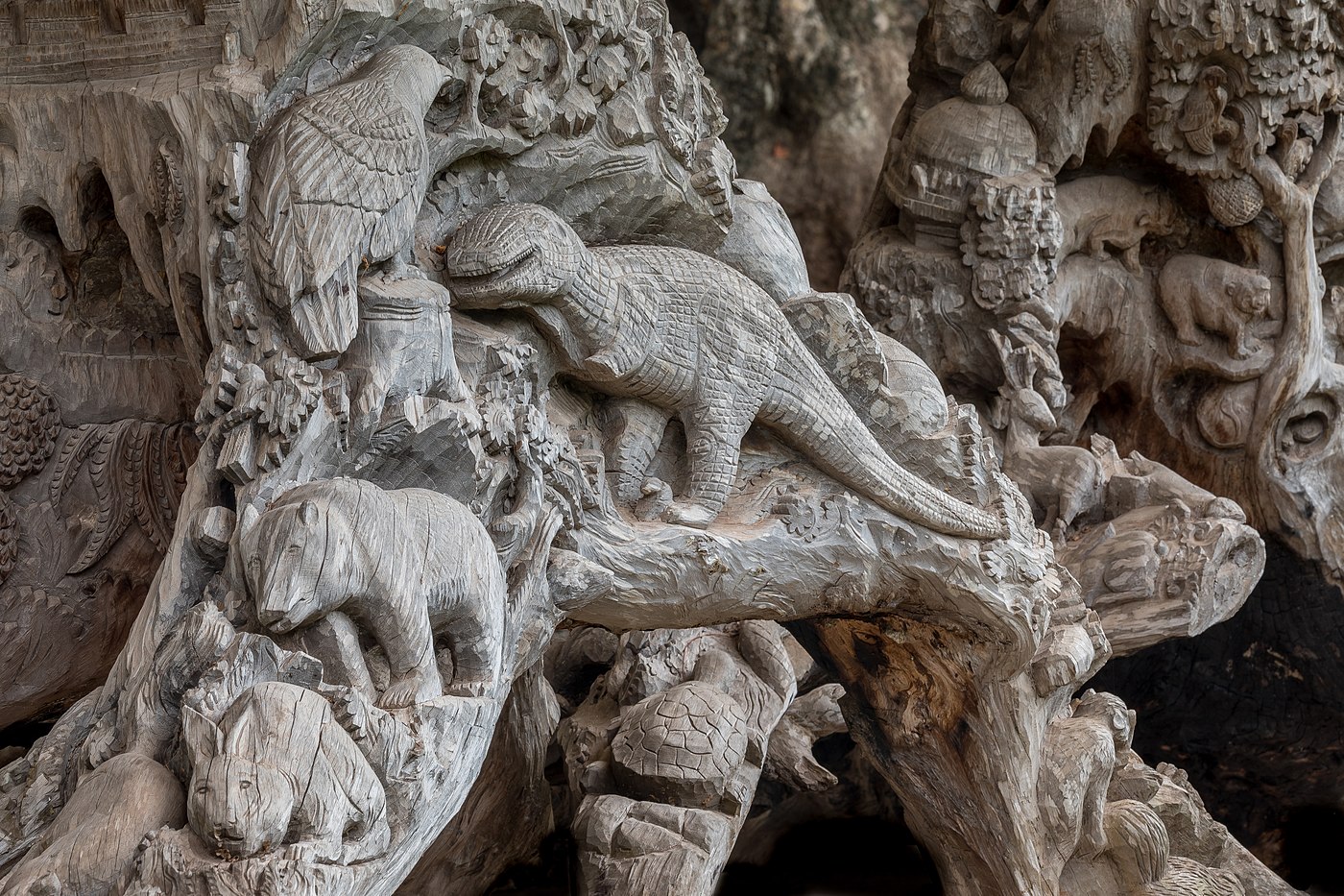 Tronc d'arbre sculpté avec des reliefs de dinosaure et animaux