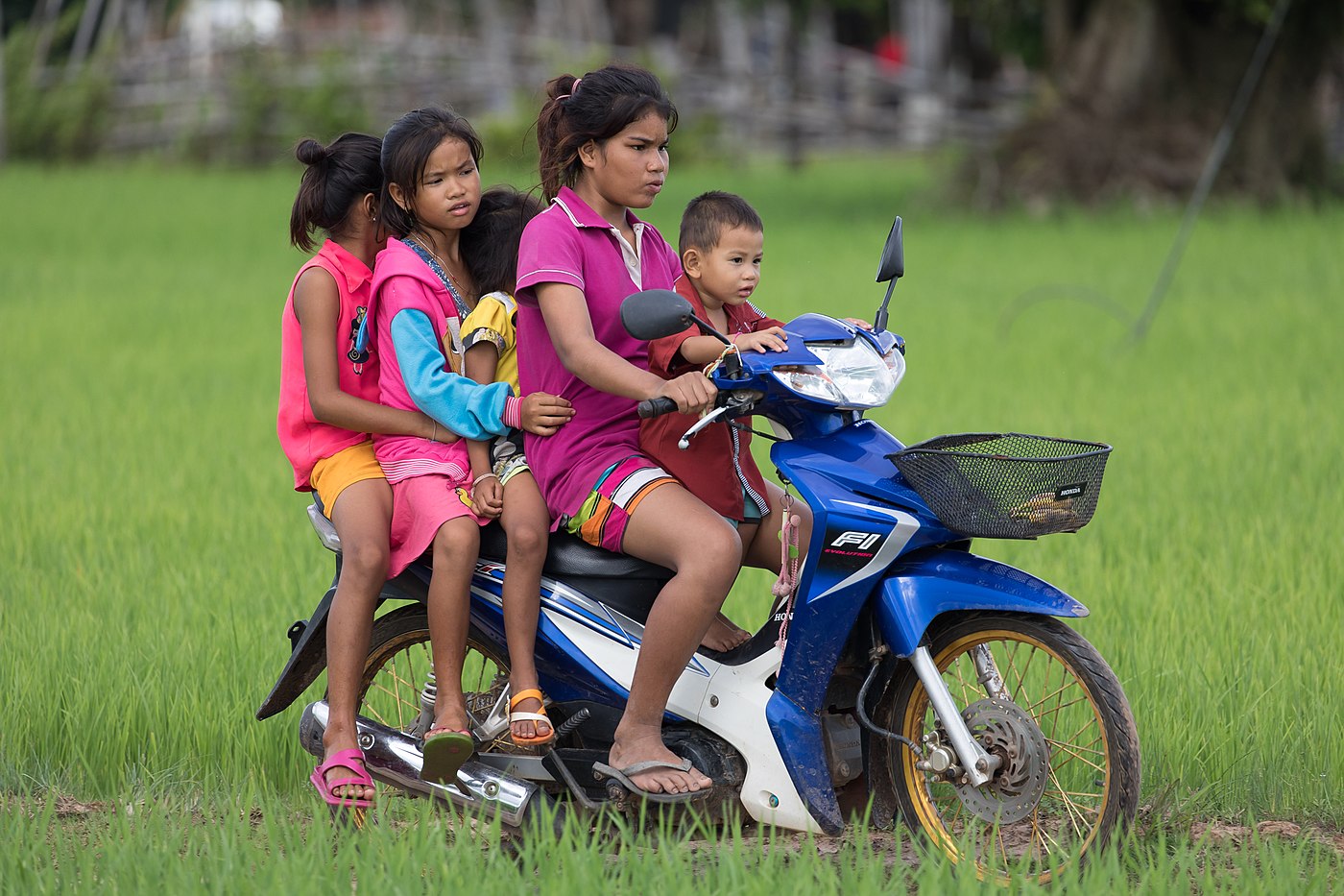 Jeune fille conduisant une moto avec quatre autres enfants passagers