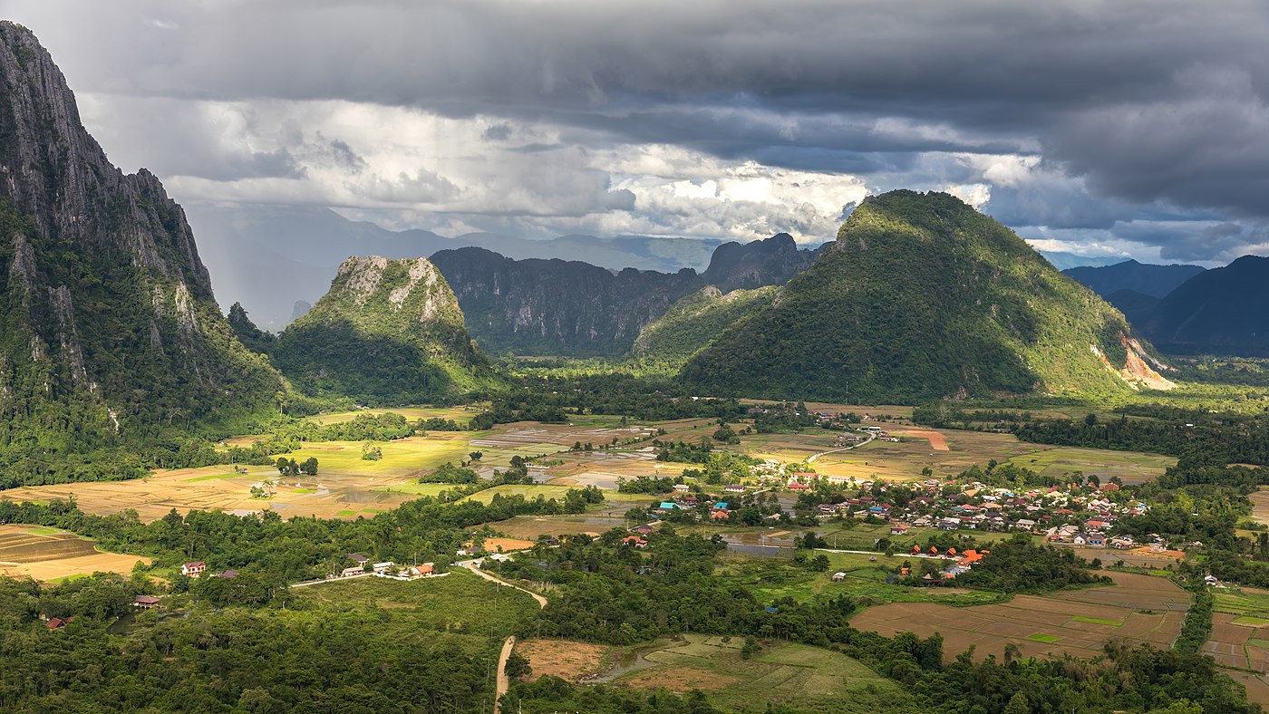 Karst peaks and green paddy fields under a stormy sky