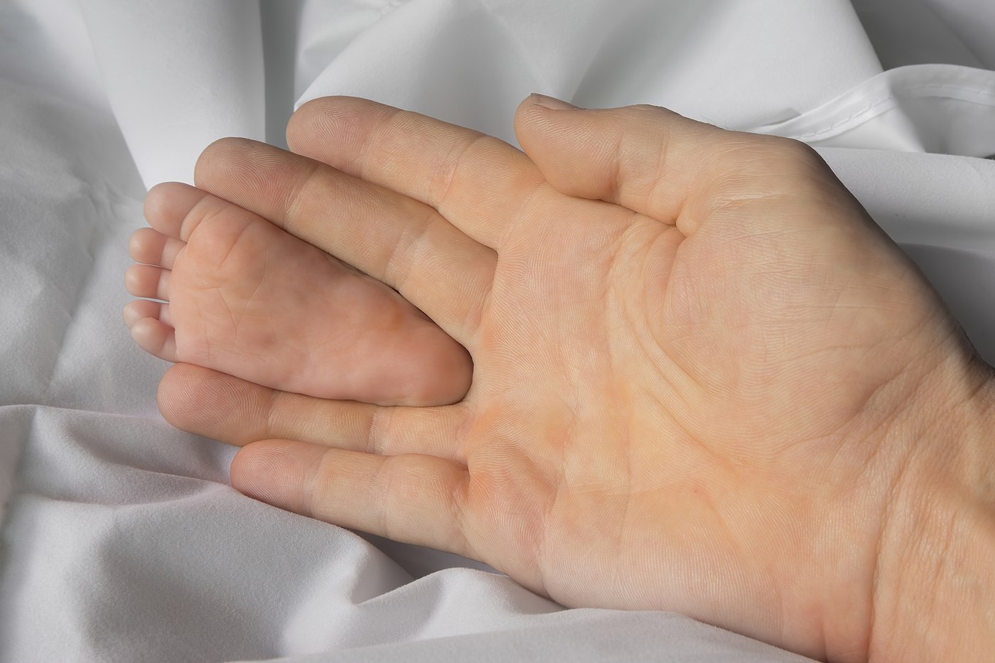 Sole of foot of a one month old infant with adult hand