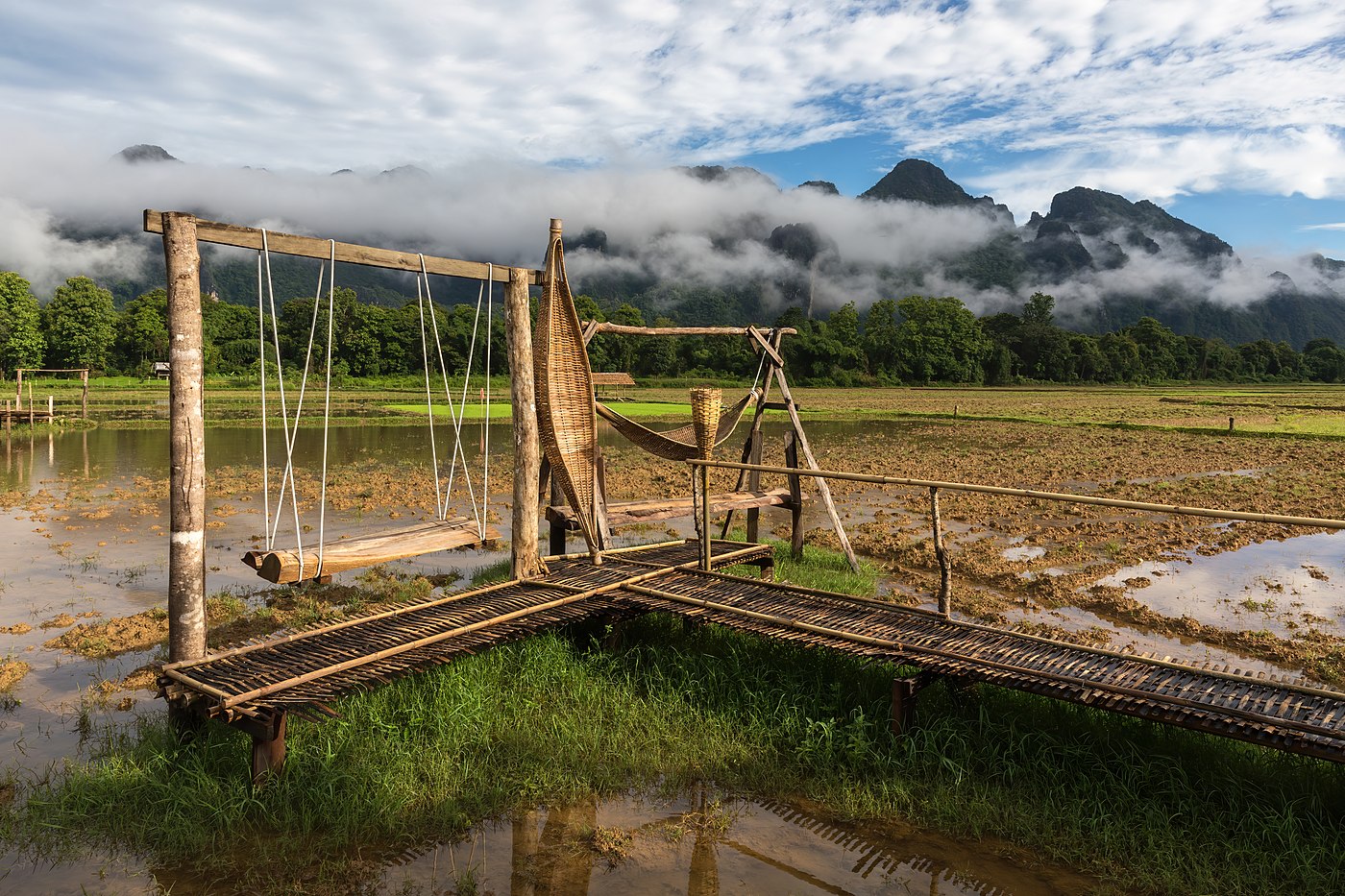 Wooden bench swing and wicker hammocks on a temporary bamboo footbridge