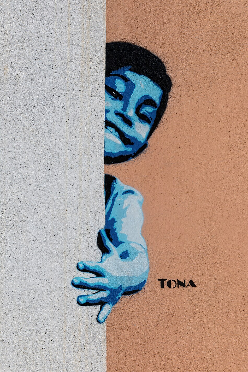 Graffiti of a boy popping out from behind a wall, by German artist Tona, in Vang Vieng, Laos
