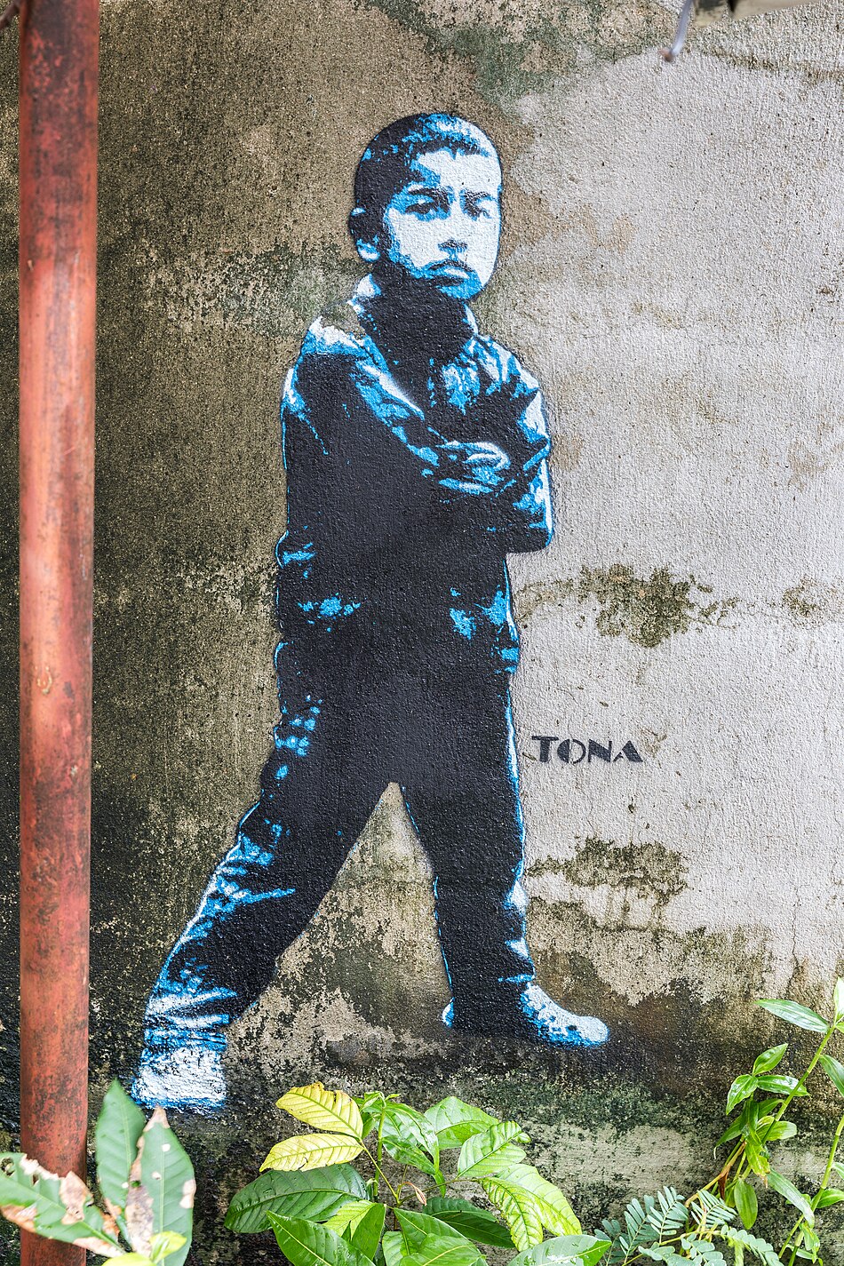 Street art stencil painting of a standing girl with crossed arms on black tiles by German artist Tona in Vientiane Laos
