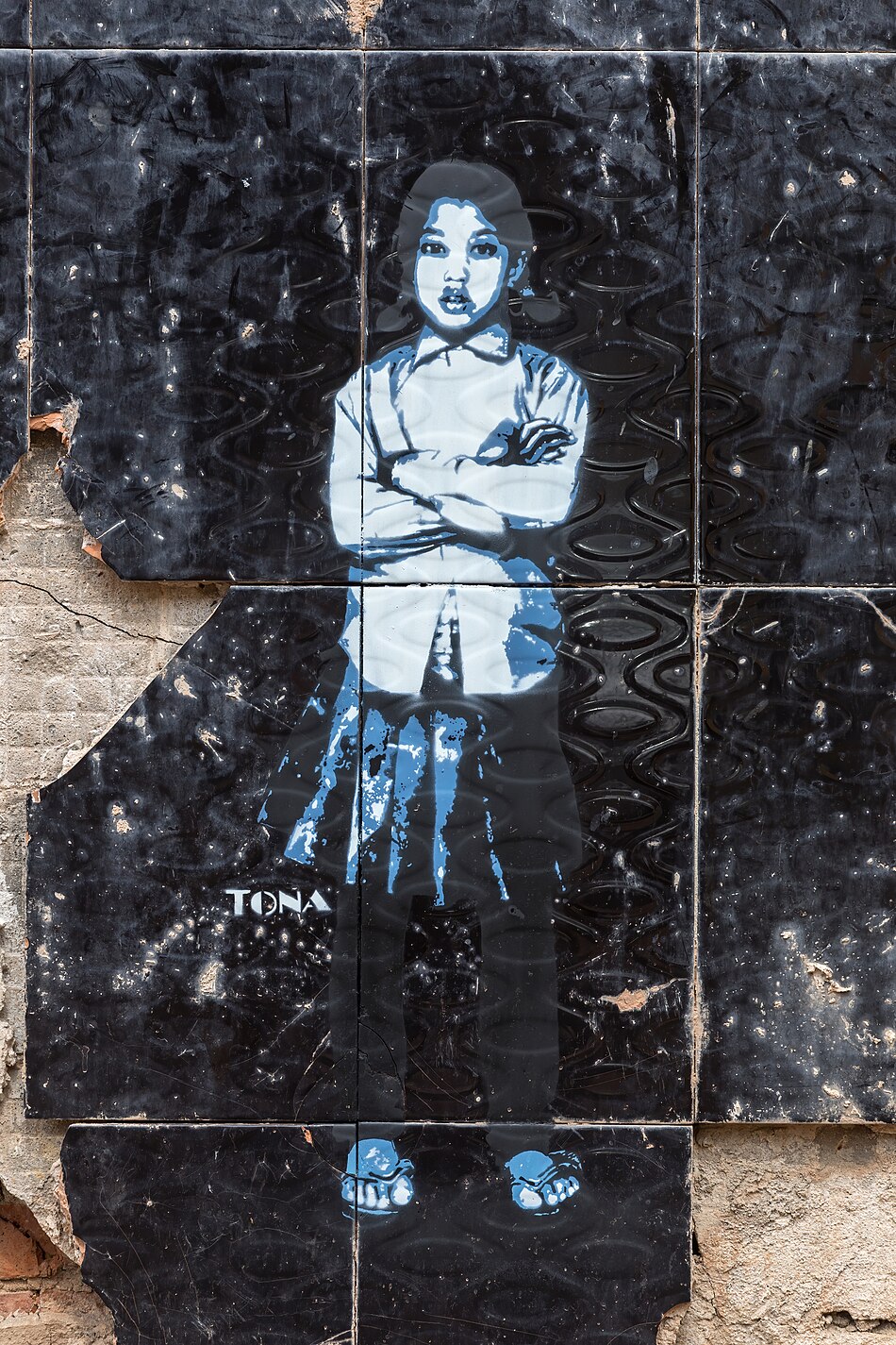 Street art stencil painting of a standing girl with crossed arms on black tiles by German artist Tona in Vientiane Laos